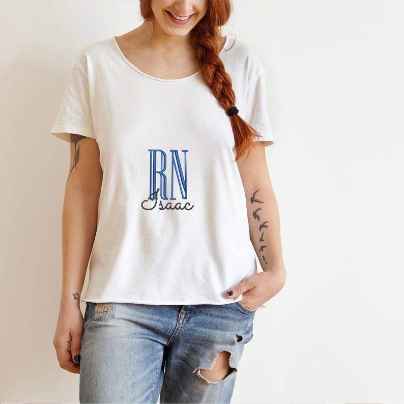 May include: White t-shirt with blue "RN" lettering and the name "Isaac" underneath. The shirt is worn by a person with a tattoo of birds on their arm.