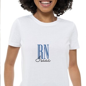 May include: White t-shirt with a blue and black embroidered design that says "RN Isaac"
