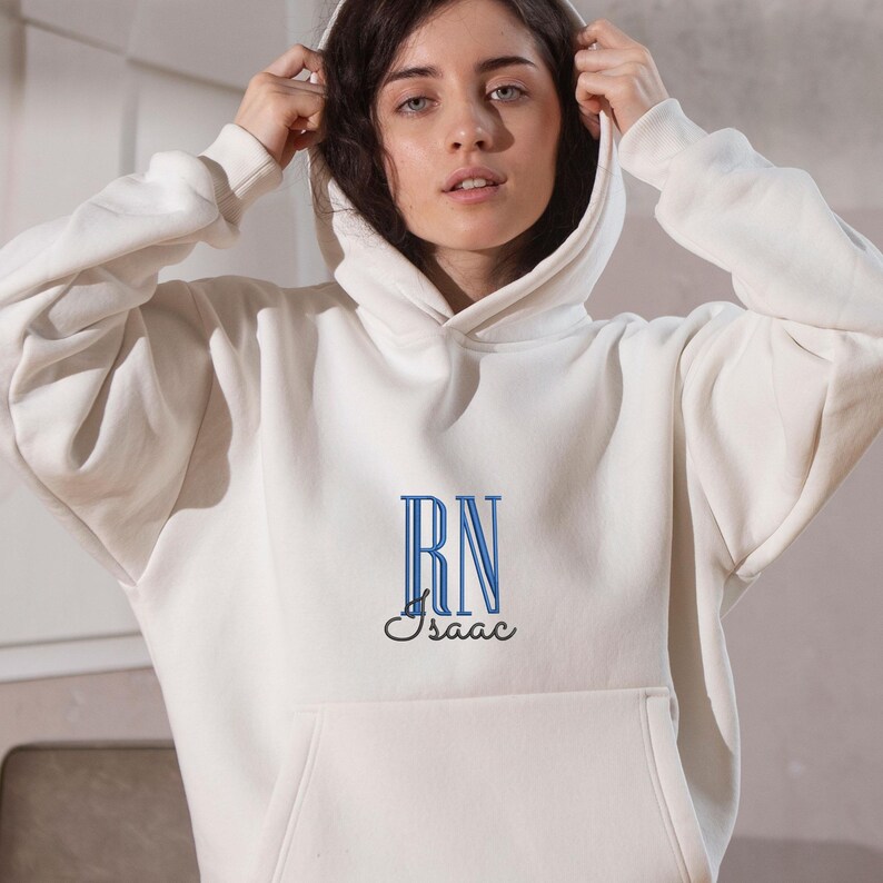 May include: White hooded sweatshirt with blue embroidered letters "RN" and the name "Isaac" underneath.