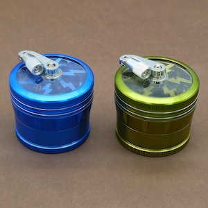 以下が含まれることがあります： 透明な蓋が付いた金属製のハーブグラインダーが2つ。1つは青、もう1つは緑です。