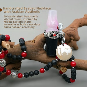 May include: A black and red beaded necklace with a silver charm featuring a mosque silhouette and the word "Miyah". The necklace is made with 99 handcrafted beads and is inspired by Middle Eastern design. It can be worn as a necklace or used as a hookah accessory.