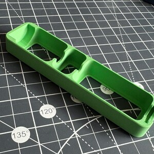 May include: A green plastic organizer with three compartments. The organizer is designed to hold small items, such as pens, pencils, or other office supplies.