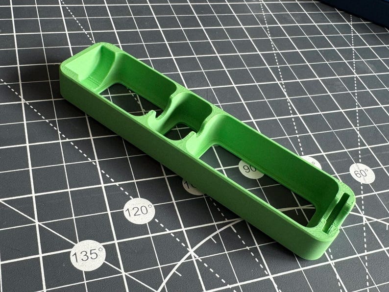 May include: A green plastic organizer with three compartments. The organizer is designed to hold small items, such as pens, pencils, or other office supplies.