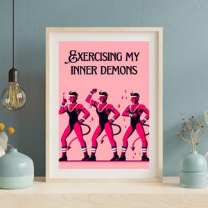 May include: A pink and black illustration of three red devils in workout attire with the text "Exercising My Inner Demons".