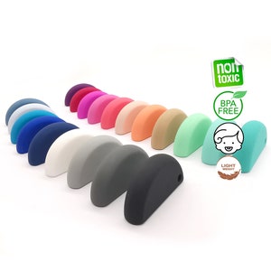 Puede incluir: Un conjunto de 16 mordedores de silicona en forma de semicírculo en varios colores, incluidos azul, verde, rosa, morado, gris y blanco. Los mordedores son libres de BPA, no tóxicos y ligeros.
