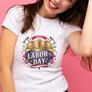 Könnte beinhalten: Weißes T-Shirt mit einem Grafikdesign aus drei goldenen Schutzhelmen, Hämmern, Schraubenschlüsseln und dem Text "Happy Labor Day" mit roten, weißen und blauen Sternen und Streifen.