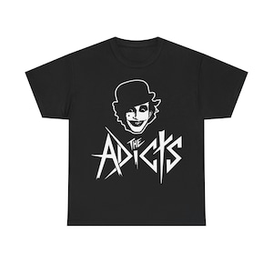 May include: Black t-shirt featuring a white graphic of a person in a bowler hat with a sinister grin, and the band name "The Adicts" in a stylized font. The design is centered on the front of the shirt.