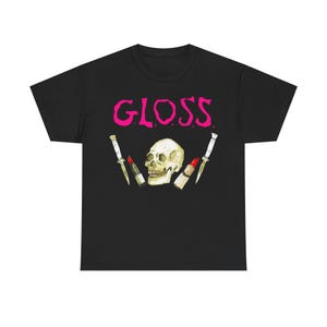 May include: Black t-shirt with the word "GLOSS" in bright pink, above a skull and two lipstick tubes with knives. The design is centered on the shirt.