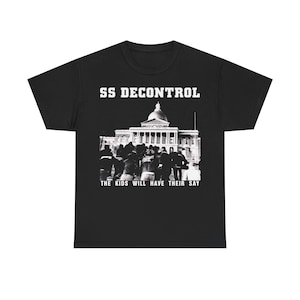 Pode incluir: T-shirt preta com o texto "SS DECONTROL" acima de uma imagem a preto e branco de um edifício e uma multidão de pessoas. O texto "THE KIDS WILL HAVE THEIR SAY" está abaixo da imagem.