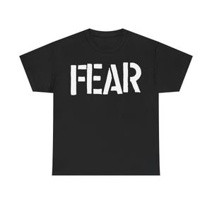 May include: Black t-shirt with the word "FEAR" printed in large, white, block letters across the chest. The shirt has short sleeves and a crew neck.