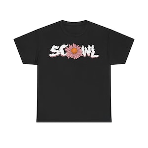 Può includere: T-shirt nero con la scritta "SCONL" in bianco, a forma di nuvola, e un fiore di margherita rosa e arancione al centro. La maglietta è un classico girocollo.