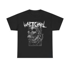 May include: Black t-shirt featuring the band name "WHITECHAPEL" in white, stylized lettering above a detailed grayscale skull graphic. The skull is surrounded by a floral design within a rectangular frame.