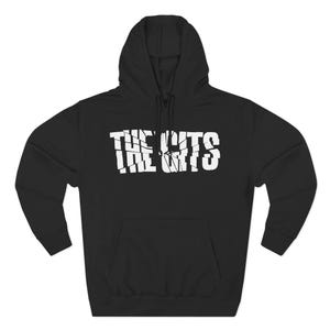 May include: Black hooded sweatshirt with the text "THE GUTS" in white block letters across the chest. The text has a distressed, cracked appearance. The sweatshirt has a drawstring hood and a front pocket.