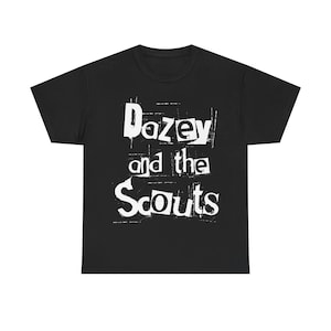 May include: Black t-shirt featuring the white text "Dazey and the Scouts" in a distressed, grunge-style font. The text is centred on the front. The shirt has a crew neck and short sleeves.