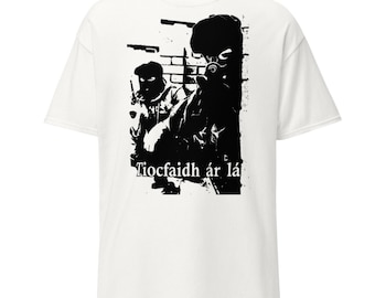 May include: White t-shirt featuring a black and white graphic of two figures wearing masks and tactical gear. The graphic includes the text "Tiocfaidh ár lá" in a stylized font, with a background of what appears to be weapons.