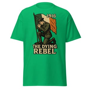 May include: Green t-shirt featuring a graphic of a kneeling soldier with an Irish flag and the text "1916" and "THE DYING REBEL". The soldier is wearing a military uniform. The design is in shades of brown, green, and orange.