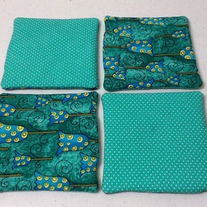 Puede incluir: Cuatro posavasos cuadrados de tela. Dos son de color turquesa con lunares blancos. Los otros dos presentan un estampado de escobas de bruja azules y amarillas sobre un fondo turquesa. Una divertida adici&oacute;n a cualquier hogar.
