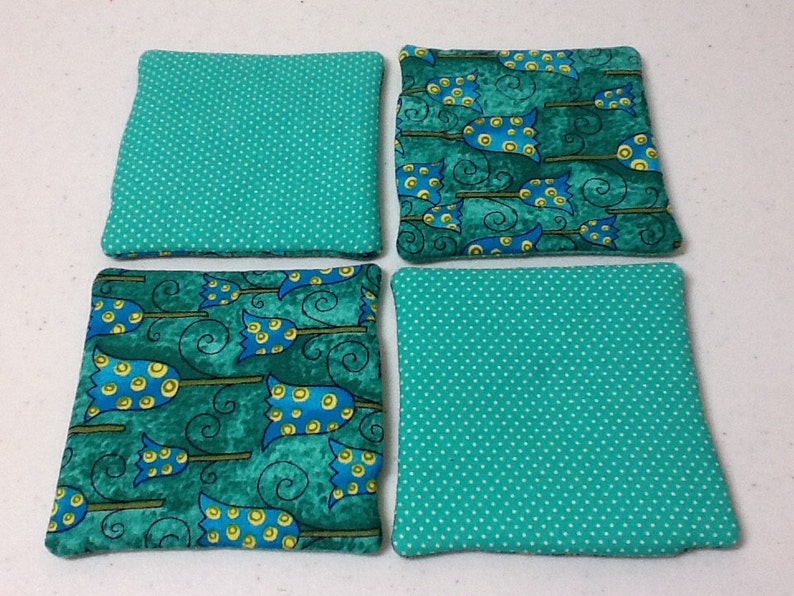 Puede incluir: Cuatro posavasos cuadrados de tela. Dos son de color turquesa con lunares blancos. Los otros dos presentan un estampado de escobas de bruja azules y amarillas sobre un fondo turquesa. Una divertida adici&oacute;n a cualquier hogar.