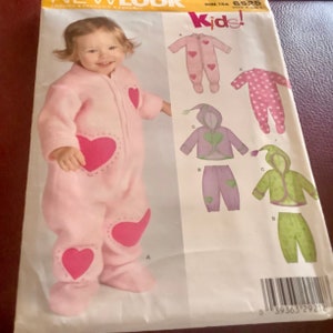 May include: A pink baby's jumpsuit with large pink heart appliques. The image also shows a pattern for children's clothing, including a jumpsuit, jacket, and pants. The word "Kids!" is printed in red.