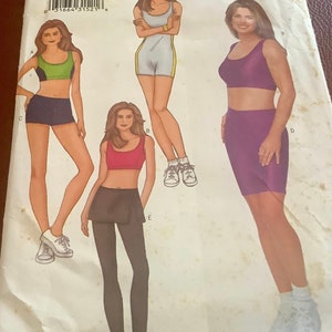May include: A sewing pattern featuring illustrations of athletic wear. The designs include a sports bra and shorts set, a romper with a yellow stripe, and leggings with a skirt overlay. The pattern is for sizes 6-8-10.