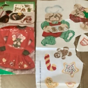 May include: A no-sew Christmas craft kit featuring a red dress with a bear design and the text "Cookie Bear". Includes fabric cutouts of gingerbread men, cookies, and a bear chef. The kit is designed for festive holiday projects.