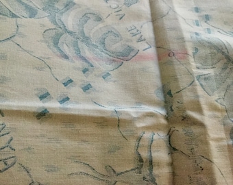 Op de afbeelding: Crèmekleurige stof met een kaartachtig ontwerp met blauwe en roze accenten. De stof heeft een getextureerde uitstraling, met zichtbare details van een kaart, waaronder de woorden "KENYA" en "LAKE VICTORIA".