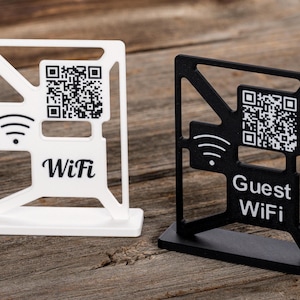 Può includere: Due cartelli da tavolo in bianco e nero con un codice QR e un simbolo wifi. Il cartello bianco dice "WiFi" e il cartello nero dice "Guest WiFi".