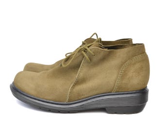 May include: A pair of olive green suede ankle boots with lace-up closures and a thick black rubber sole.