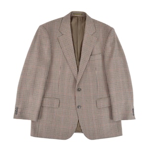 May include: A brown and tan houndstooth blazer with red detailing. The jacket features a notched lapel, two front pockets, and a two-button closure. The sleeves have three buttons at the cuff. The interior lining is a solid tan colour.