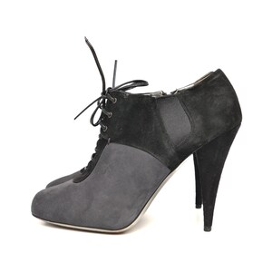May include: Black suede ankle boots with a lace-up front and a high stiletto heel.