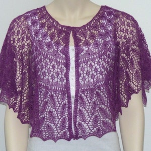 May include: A purple crocheted shawl with a delicate lace pattern. The shawl has a V-neck opening and short sleeves.