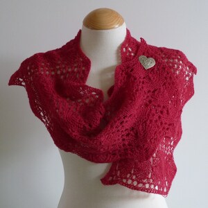May include: A red crocheted shawl with a delicate lace pattern and a silver heart-shaped pin.