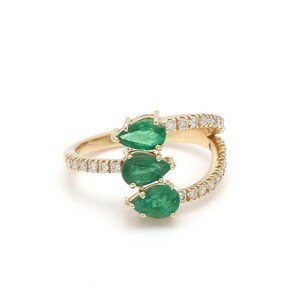 May include: A gold ring with three pear-shaped emerald gemstones and a band of pave-set diamonds.