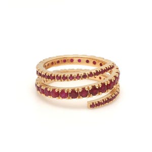 May include: A gold ring with two bands of ruby red stones. The bands are intertwined and spiral around the finger.