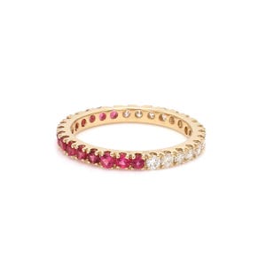 May include: A gold band ring with a half eternity setting of red gemstones and a half eternity setting of white gemstones.