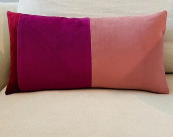 Puede incluir: Una almohada rectangular con un diseño de tela de terciopelo rosa, magenta y rojo.