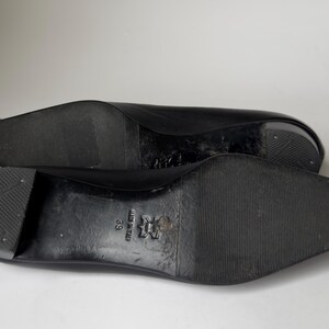 May include: Black leather shoes with a pointed toe and a rubber sole. The shoes have a size 39 label on the sole.