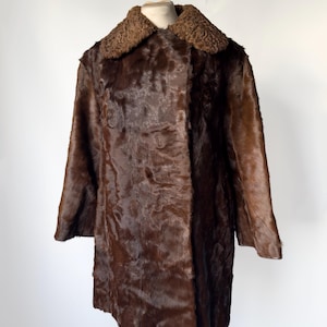 May include: A vintage brown fur coat with a textured appearance. The coat features a contrasting dark brown, textured collar. The coat is displayed on a mannequin, showcasing its full length and design. A classic outerwear piece.