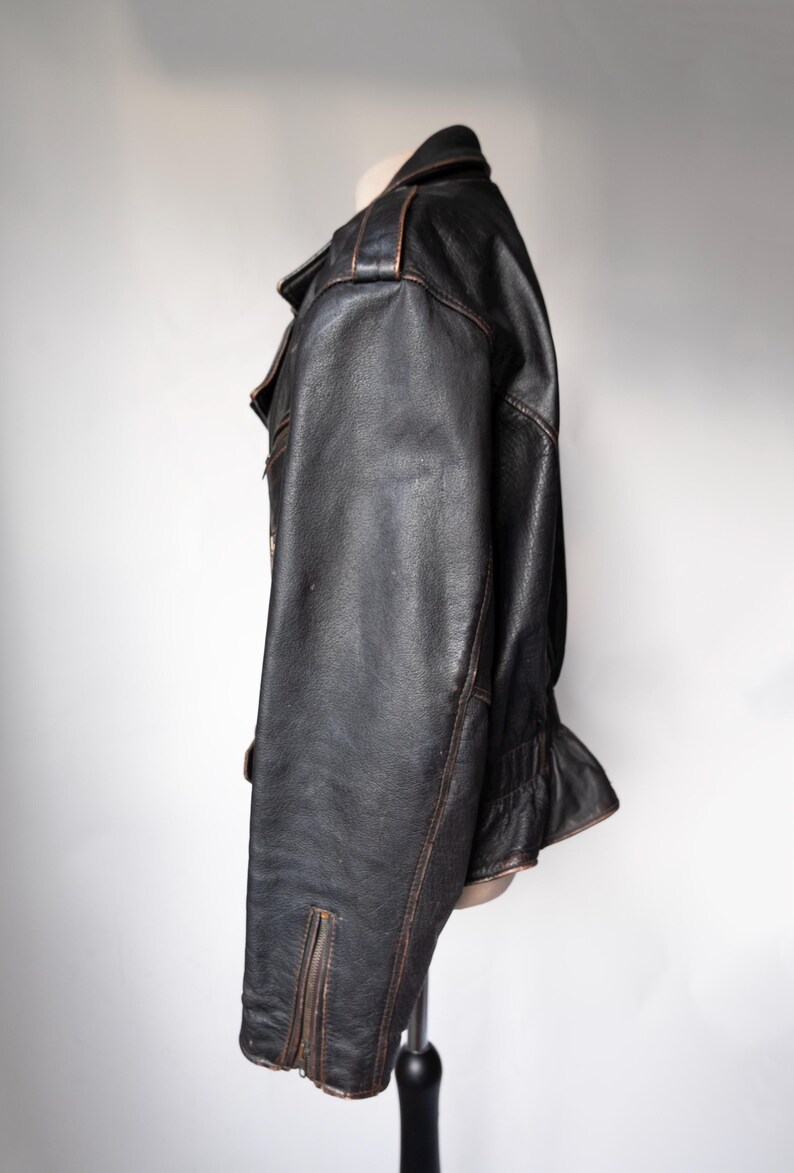 May include: Black leather jacket with a classic design. The jacket features a notched collar, a zipper closure, and a fitted silhouette. The leather has a distressed look with brown accents, giving it a vintage feel.