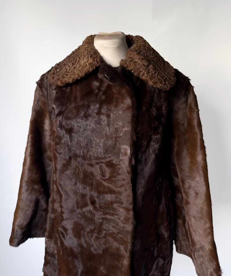 May include: A dark brown fur coat with a contrasting textured collar. The coat is displayed on a mannequin, showcasing its long length and button closure. The fur appears soft and luxurious, with a rich, deep color.