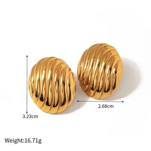 Może przedstawiać: Para złotych kolczyków z fakturowanym wzorem w kształcie spirali. Kolczyki mają średnicę 3,23 cm i ważą 16,71 grama.