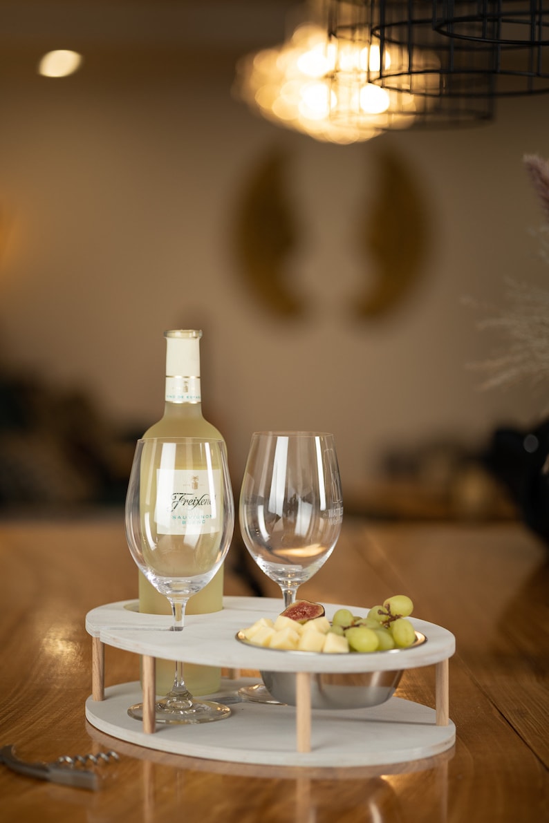 May include: A white wine bottle with a white label that says "Freixenet" on a white serving tray with two wine glasses and a bowl of fruit. The tray has a wooden base.