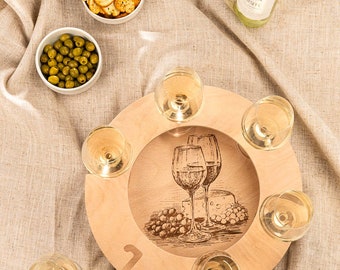 May include: A wooden wine glass holder with a design of grapes and cheese. The holder has six slots for wine glasses and is on a beige tablecloth with a bottle of wine, olives, and crackers.