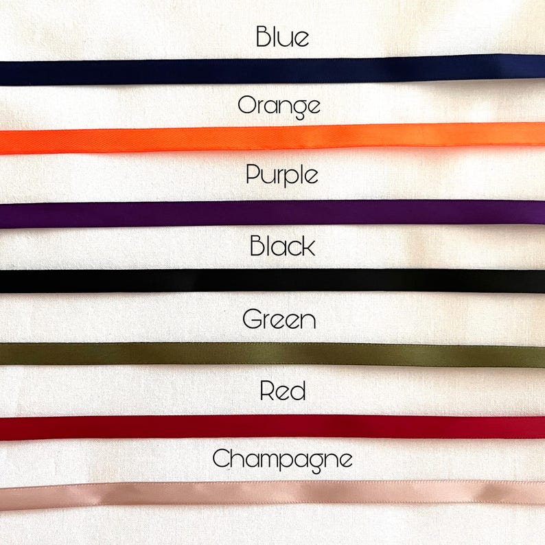May include: A collection of six horizontal satin ribbons arranged in a stack. The colors from top to bottom are labeled as Blue, Orange, Purple, Black, Green, Red, and Champagne. Each ribbon is smooth, solid-colored, and uniform in width.
