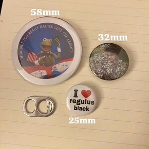 May include: A collection of buttons and a can tab. The largest button, 58mm, features Kermit the Frog with the text "Wouldn't you really rather vote for Kermit?". A 32mm button shows a person in a floral setting. A 25mm button says "I ❤️ regulus black".