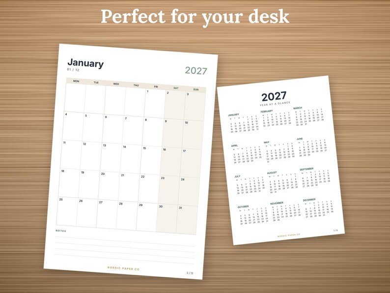 May include: A 2027 calendar set featuring a monthly view for January and a full-year "Year at a Glance" page. The monthly page includes a grid with dates, a notes section, and the text "Perfect for your desk" at the top of the white paper sheets.