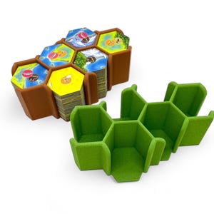 May include: Two hexagonal game tile organizers, one brown and one green. The brown organizer has six compartments and is filled with game tiles. The green organizer has six compartments and is empty.