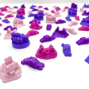 Puede incluir: Una colección de casas en miniatura e islas en varios tonos de rosa y morado. Las casas están hechas de plástico y tienen un aspecto caprichoso y de cuento de hadas. Las islas también están hechas de plástico y tienen una superficie texturizada.