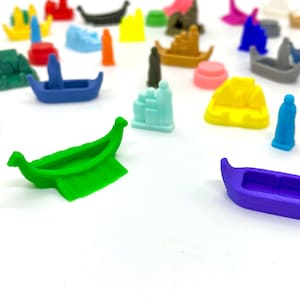 Könnte beinhalten: Eine Sammlung bunter Miniaturboote und Figuren, darunter ein grünes Boot, ein lilafarbenes Boot, ein blaues Boot, ein gelbes Boot und eine hellblaue Figur. Die Boote sind aus Plastik und haben verschiedene Formen und Größen.