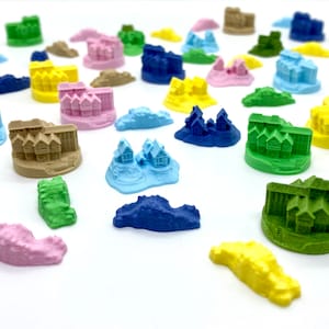 Op de afbeelding: Een verzameling kleurrijke miniatuurhuisjes op verschillende gekleurde bases. De huisjes zijn van plastic en ongeveer 2,5 cm hoog. De bases zijn van een getextureerd materiaal en ongeveer 3,8 cm in diameter.
